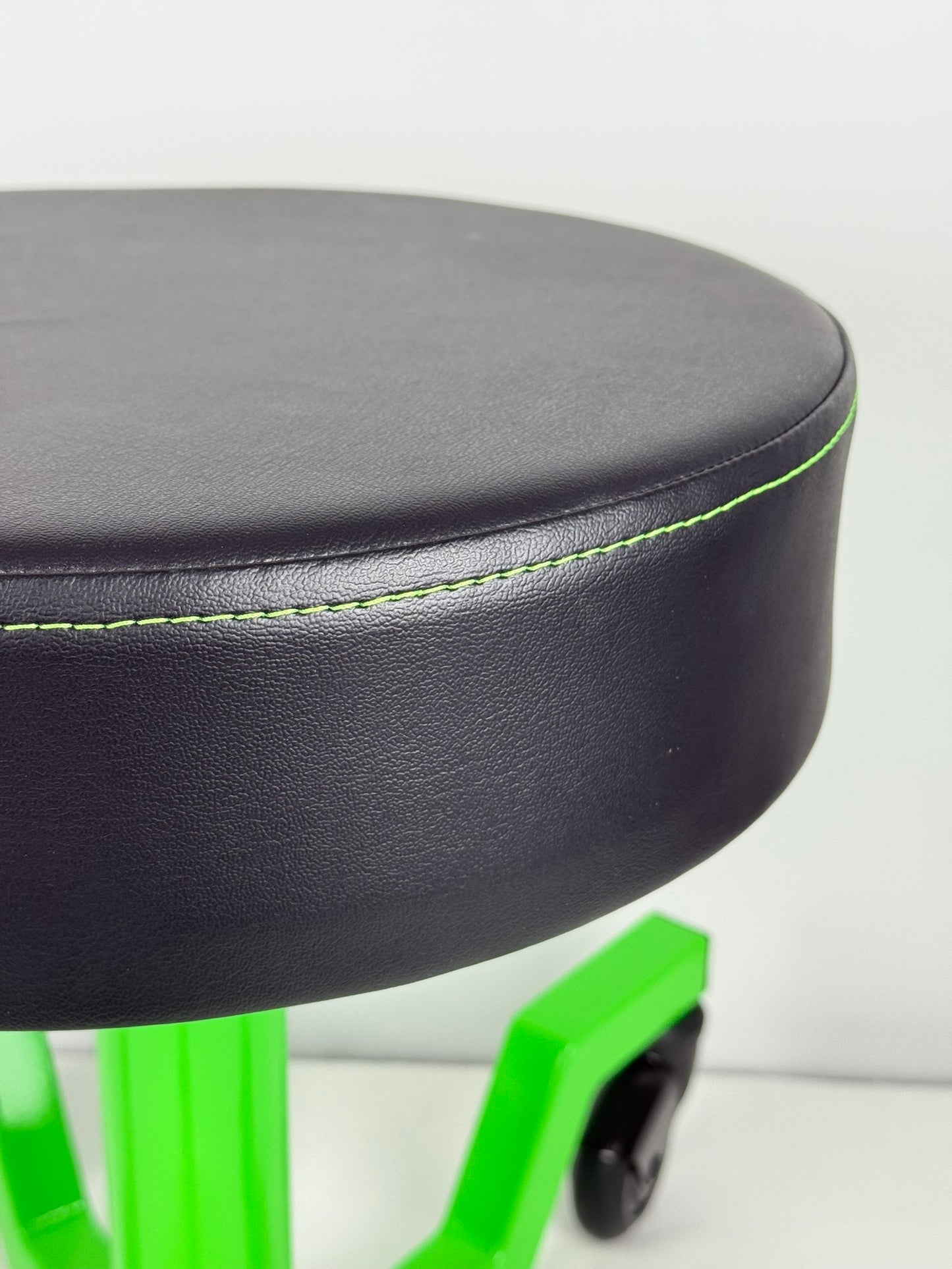 Black stool with green legs on a white background