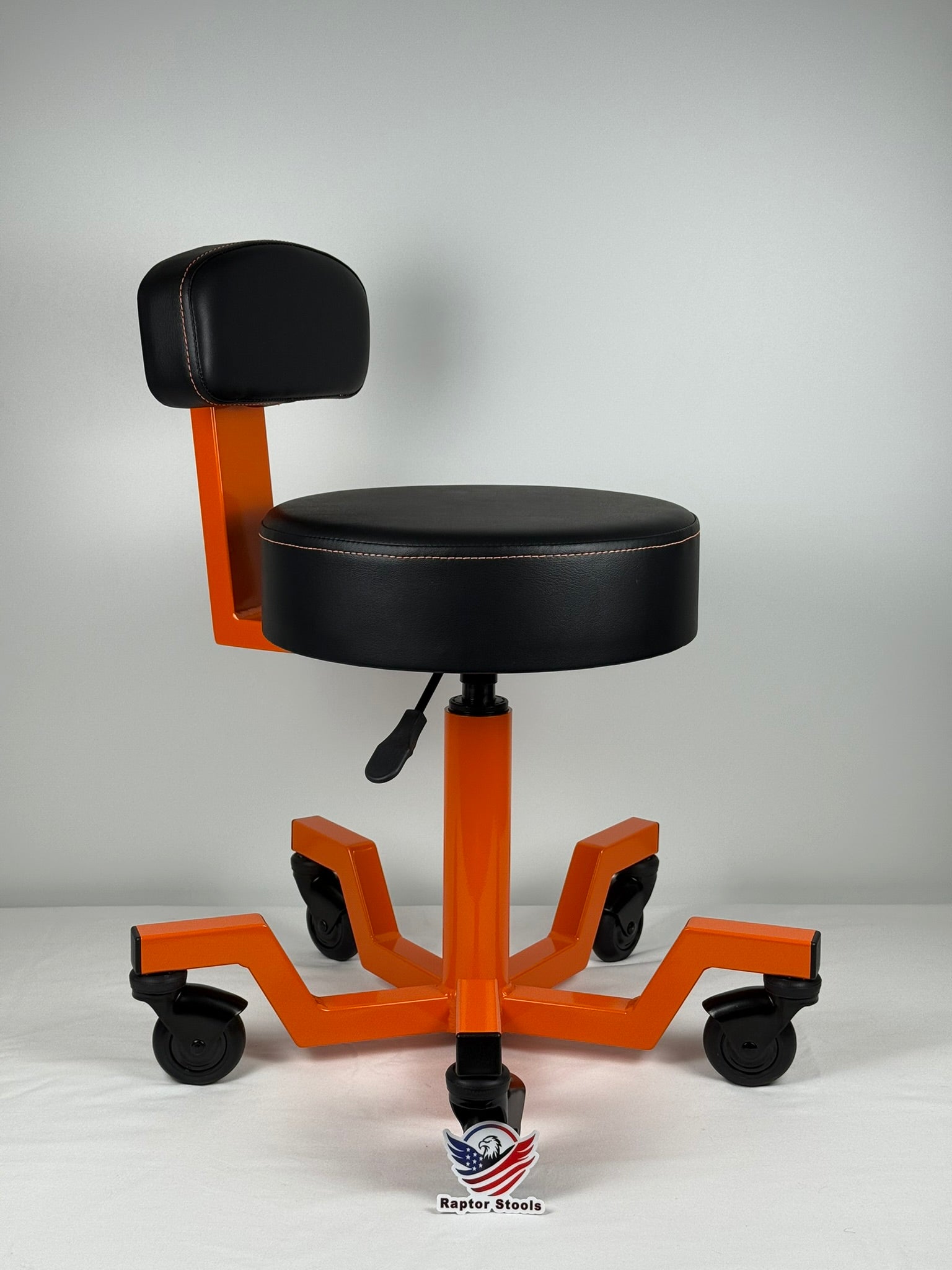 Orange and black adjustable stool with wheels on a gray background