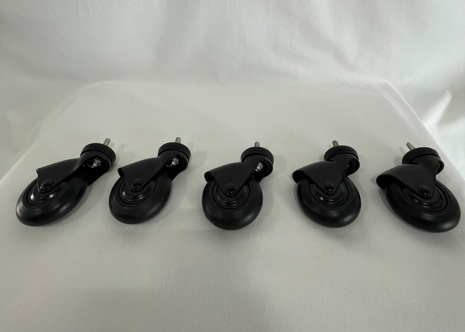 A set of five black replacement casters aligned in a row on a white background.