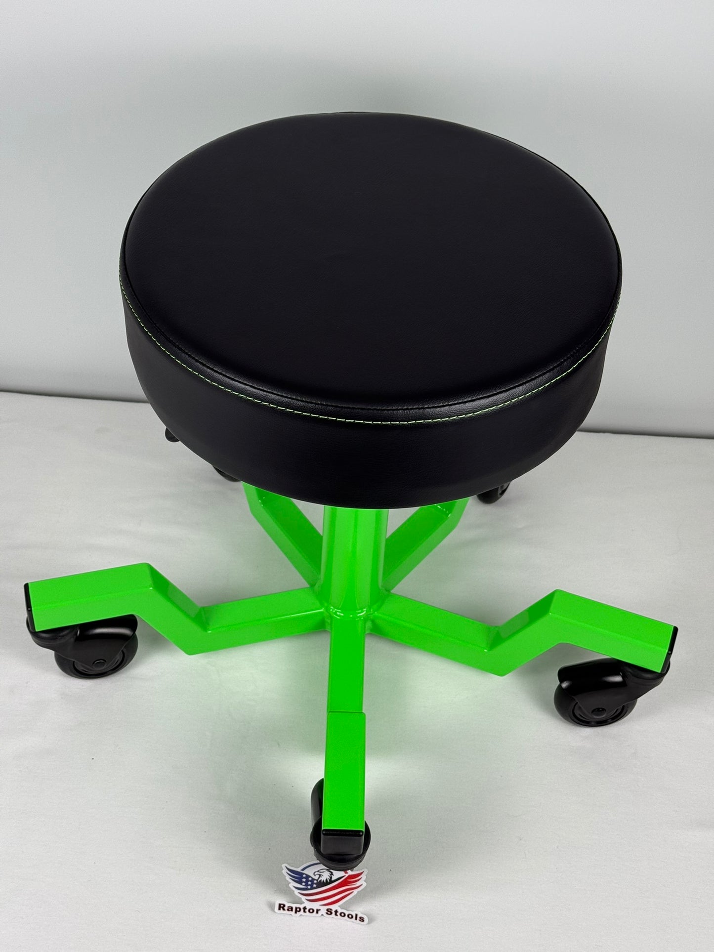 Black stool with green metal base on a white background