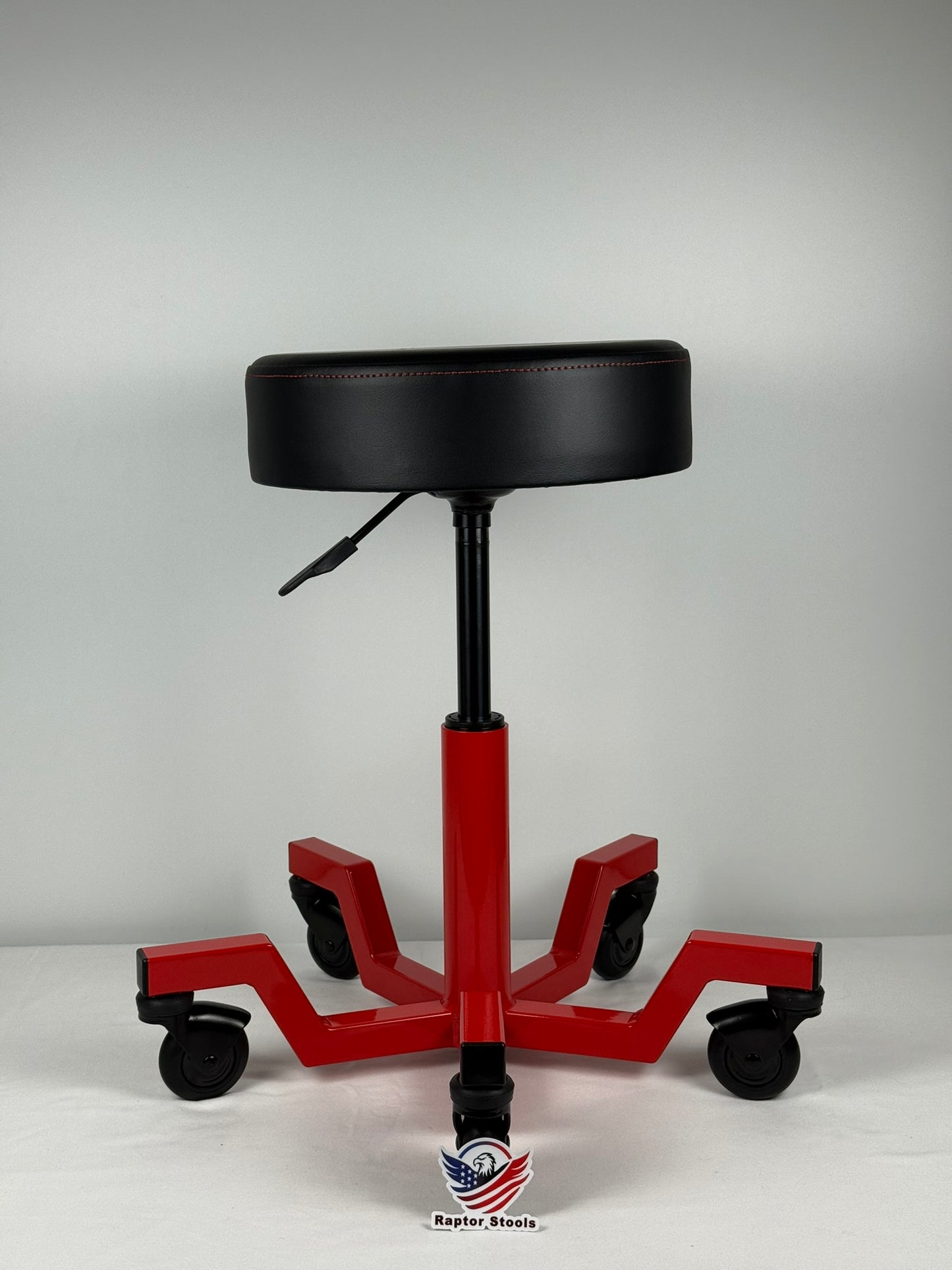 Red and black adjustable stool with wheels on a gray background