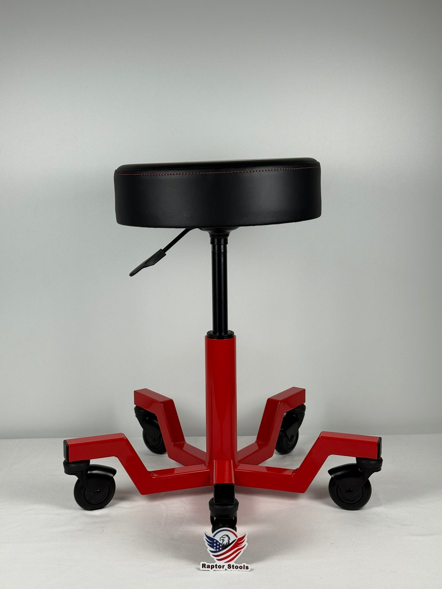 Red and black adjustable stool with wheels on a gray background