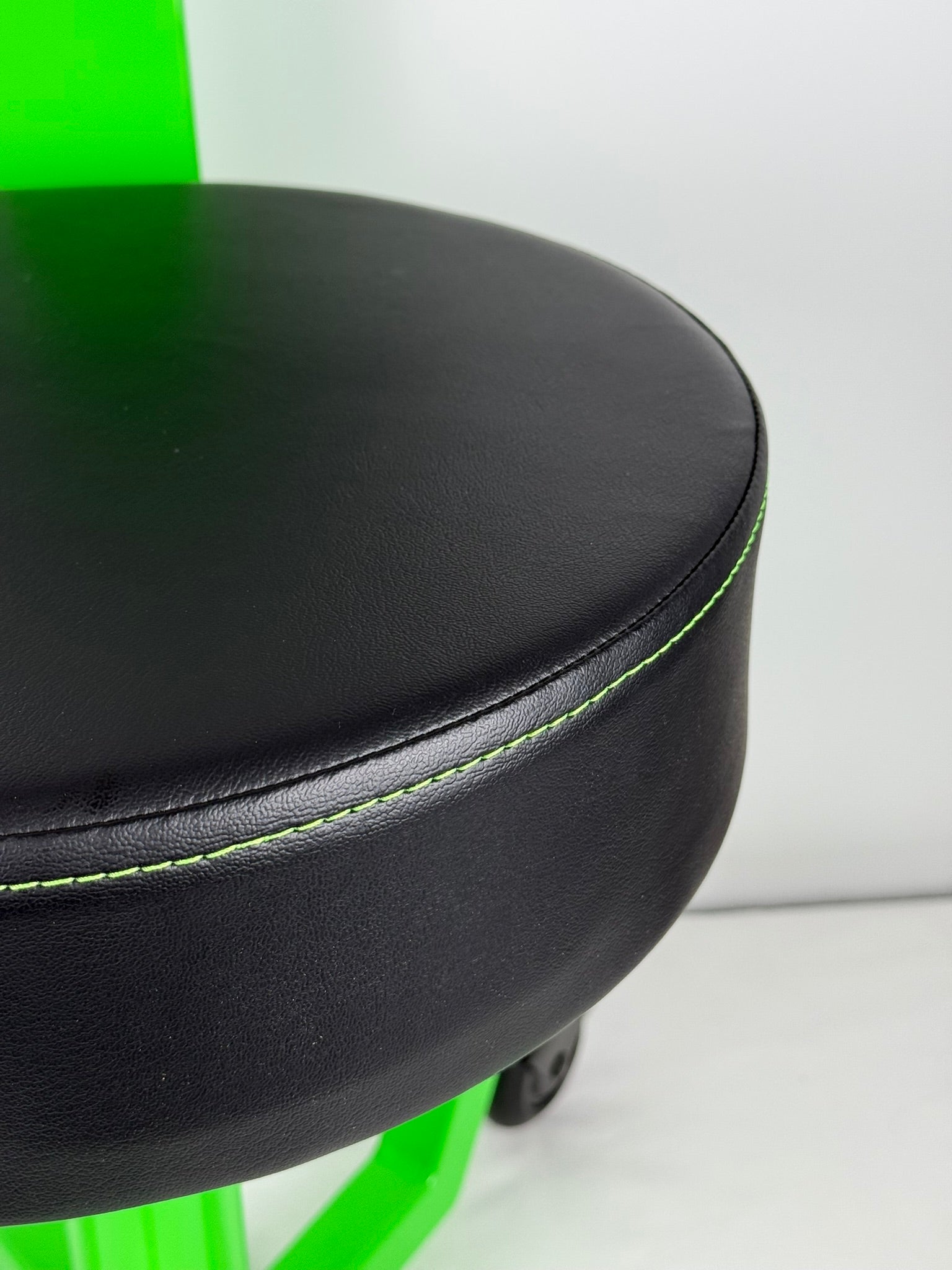 Close-up of a black seat with green trim on a white background
