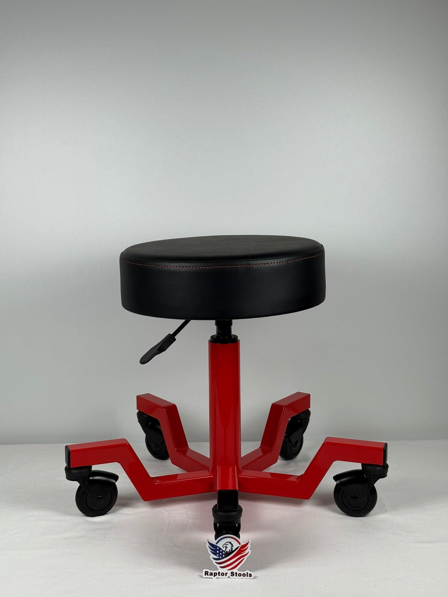 Red and black adjustable height stool on a white background